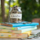 A jar of coins labelled "Education" on a stack of books.