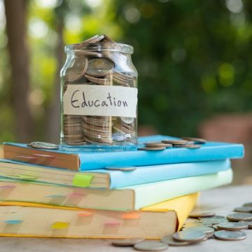 A jar of coins labelled "Education" on a stack of books.