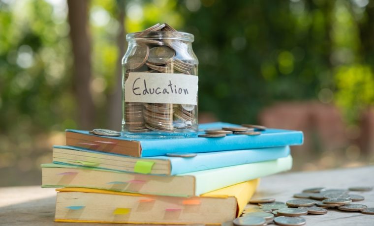 A jar of coins labelled "Education" on a stack of books.