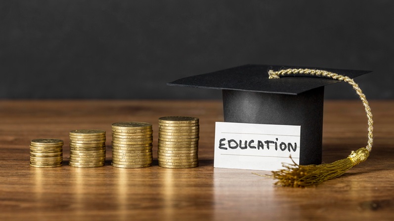 An increasing stack of coins with a graduation hat and a card with "EDUCATION" written on it.